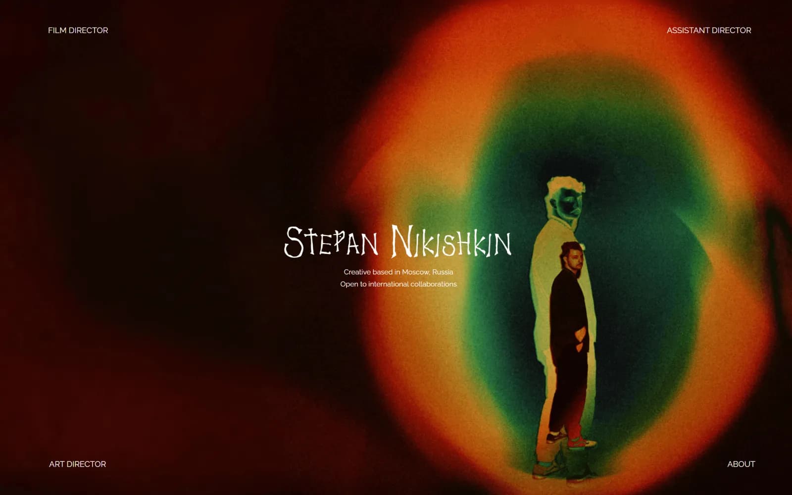 Dark portfolio home page with the director's name over a bloom of red and green light, and role links in each corner.
